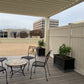 Outdoor patio area with Weatherables Davenport tan vinyl semi-privacy fencing chairs, table, and plants under a covered deck.