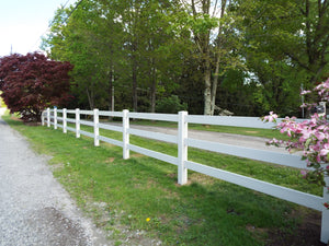 Weatherables 3-rail white vinyl horse fence along a gravel road with trees and flowers in the background