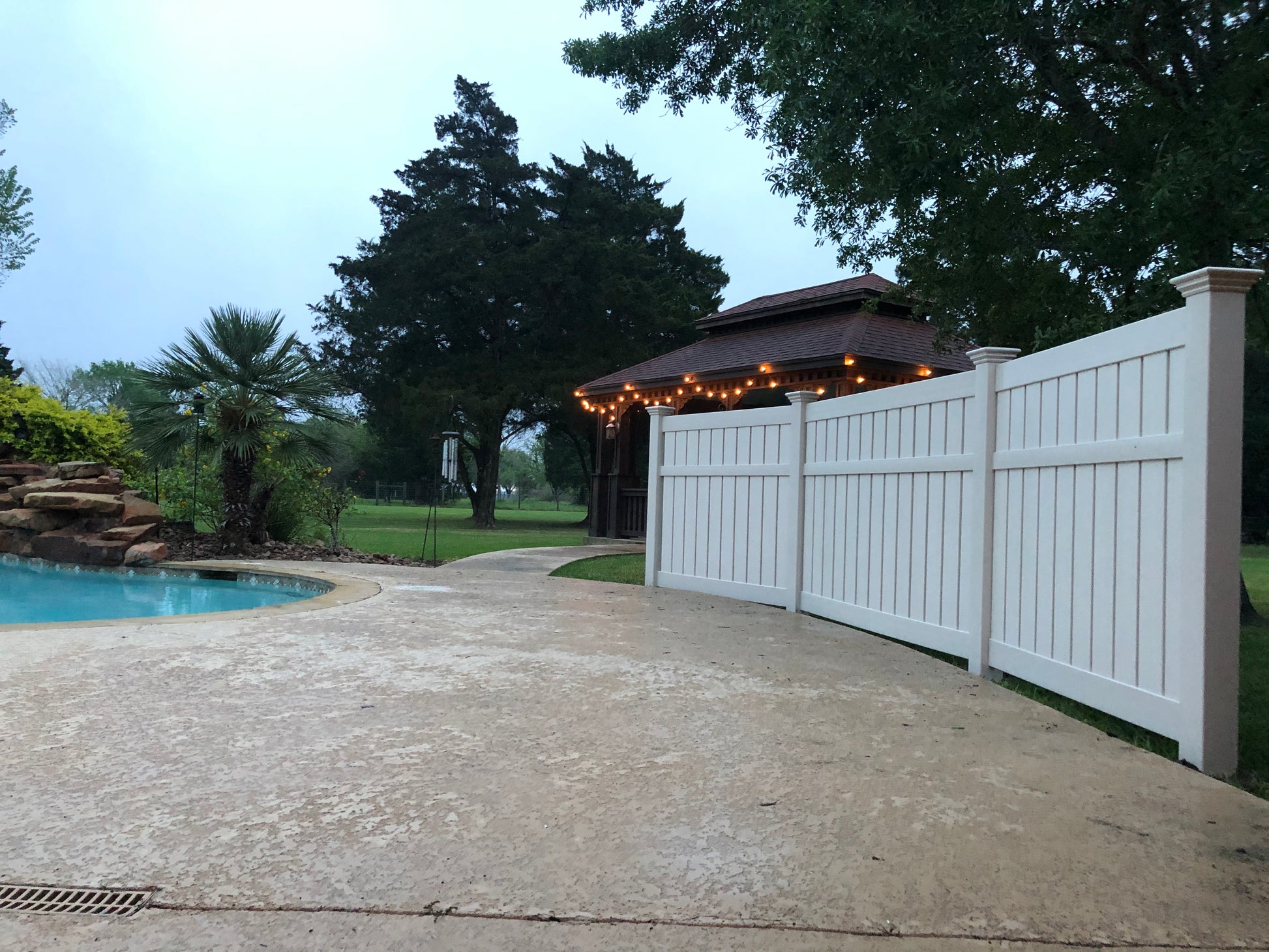 Pool area with a Weatherables Glendale white vinyl semi-privacy fence, patio, and outdoor lighting