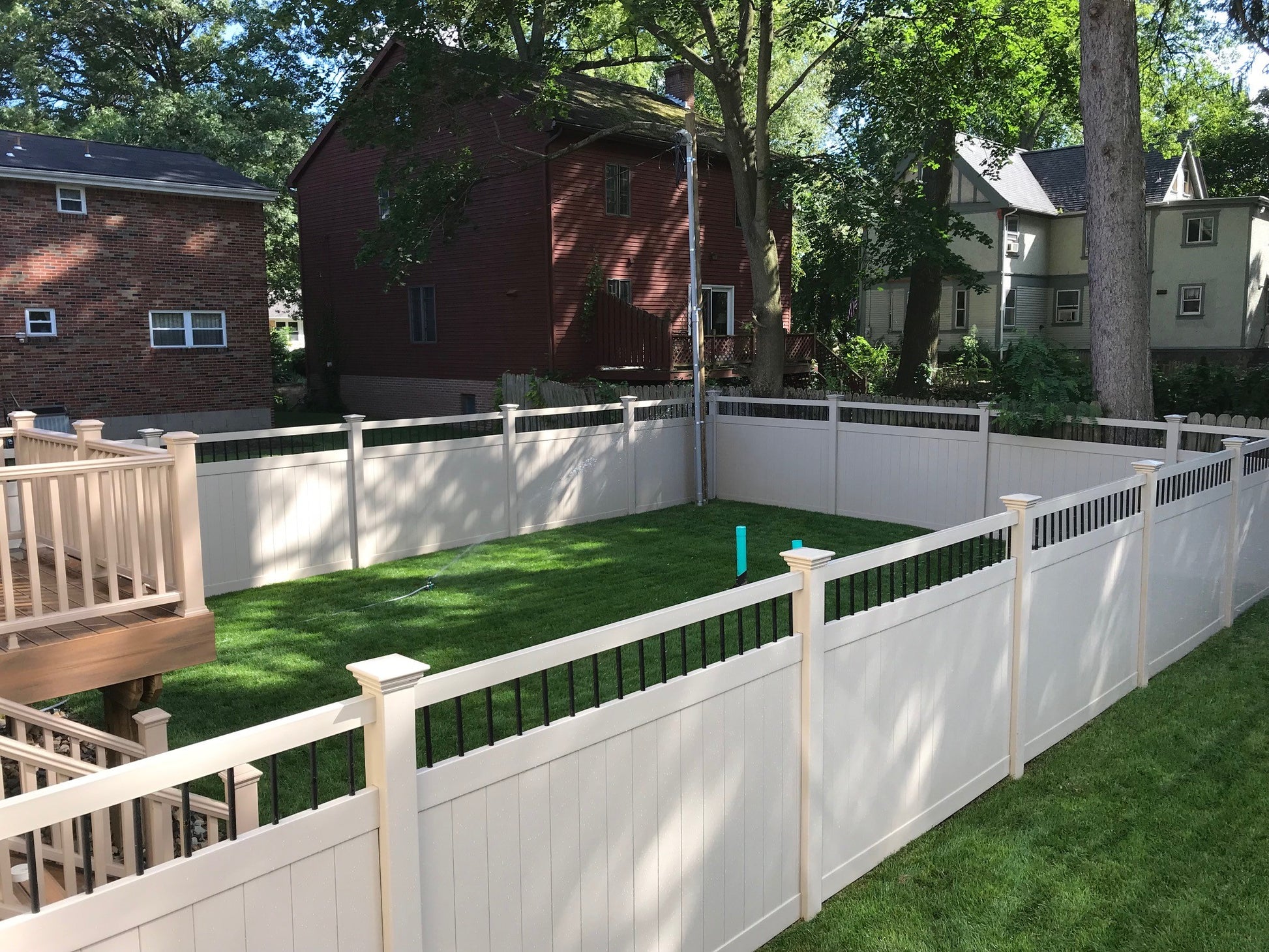 Backyard with Weatherables Bradford tan vinyl privacy fence, grass, and a house in the background