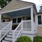 Front porch of a house with Weatherables Yorkshire white vinyl deck railings and steps, surrounded by greenery.