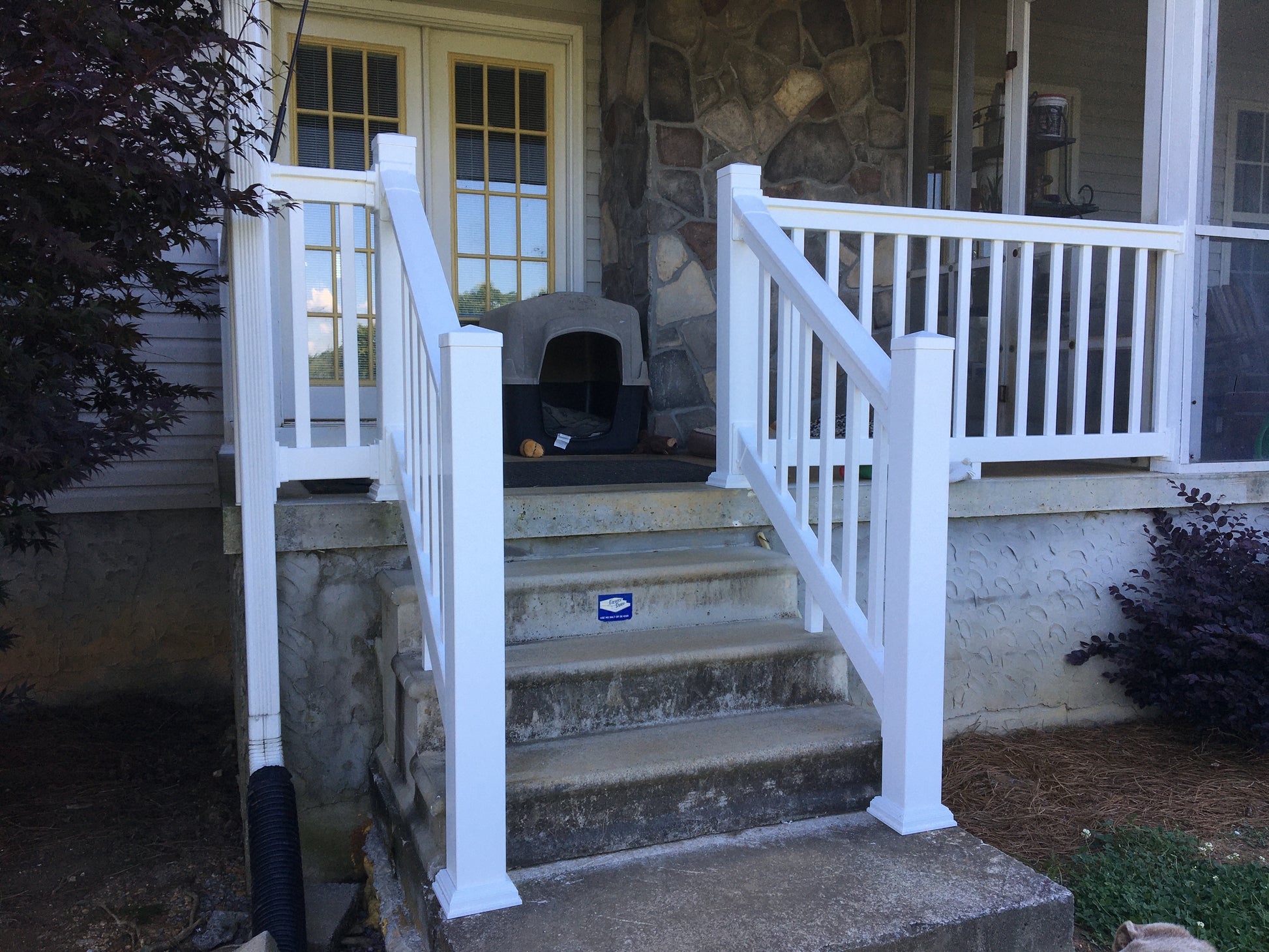 Weatherables Yorkshire white vinyl porch railing on a set of outdoor steps leading to a house entrance.