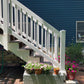 White wooden staircase with flower pots at its base against a blue house.