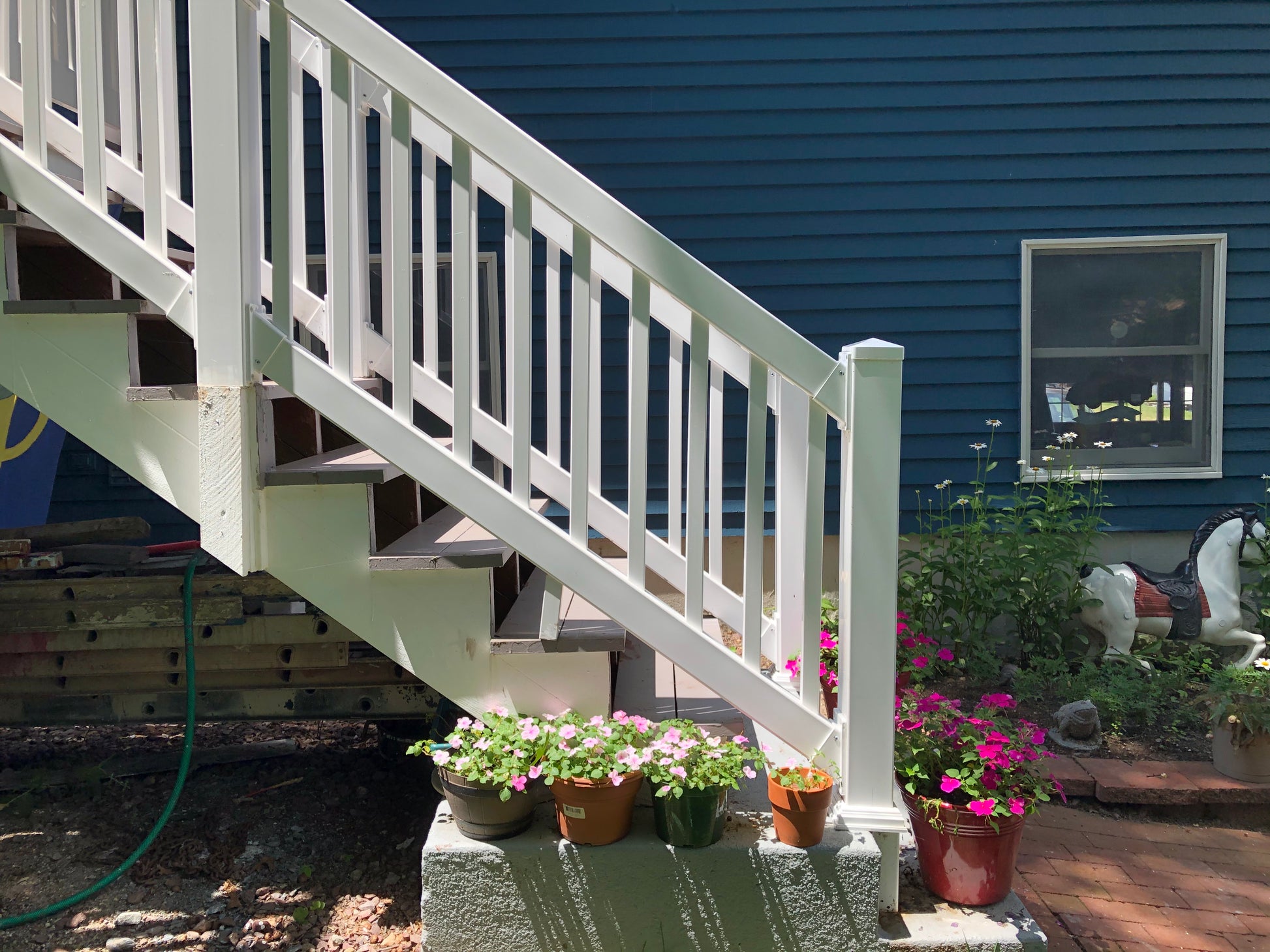 White wooden staircase with flower pots at its base against a blue house.
