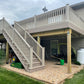 Wooden deck with stairs and Weatherables Washington khaki vinyl and stair railing leading up to it, attached to a house with a cloudy sky.