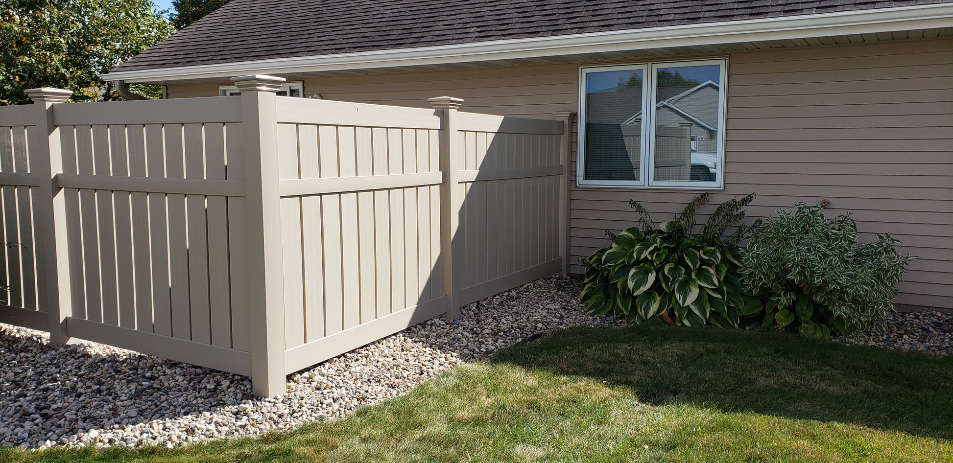 Weatherables Glendale tan vinyl semi-privacy fence and house exterior with greenery