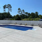 In-ground pool with lounge chairs and a Weatherables Huntington white vinyl semi-privacy fence, surrounded by trees and a clear blue sky.