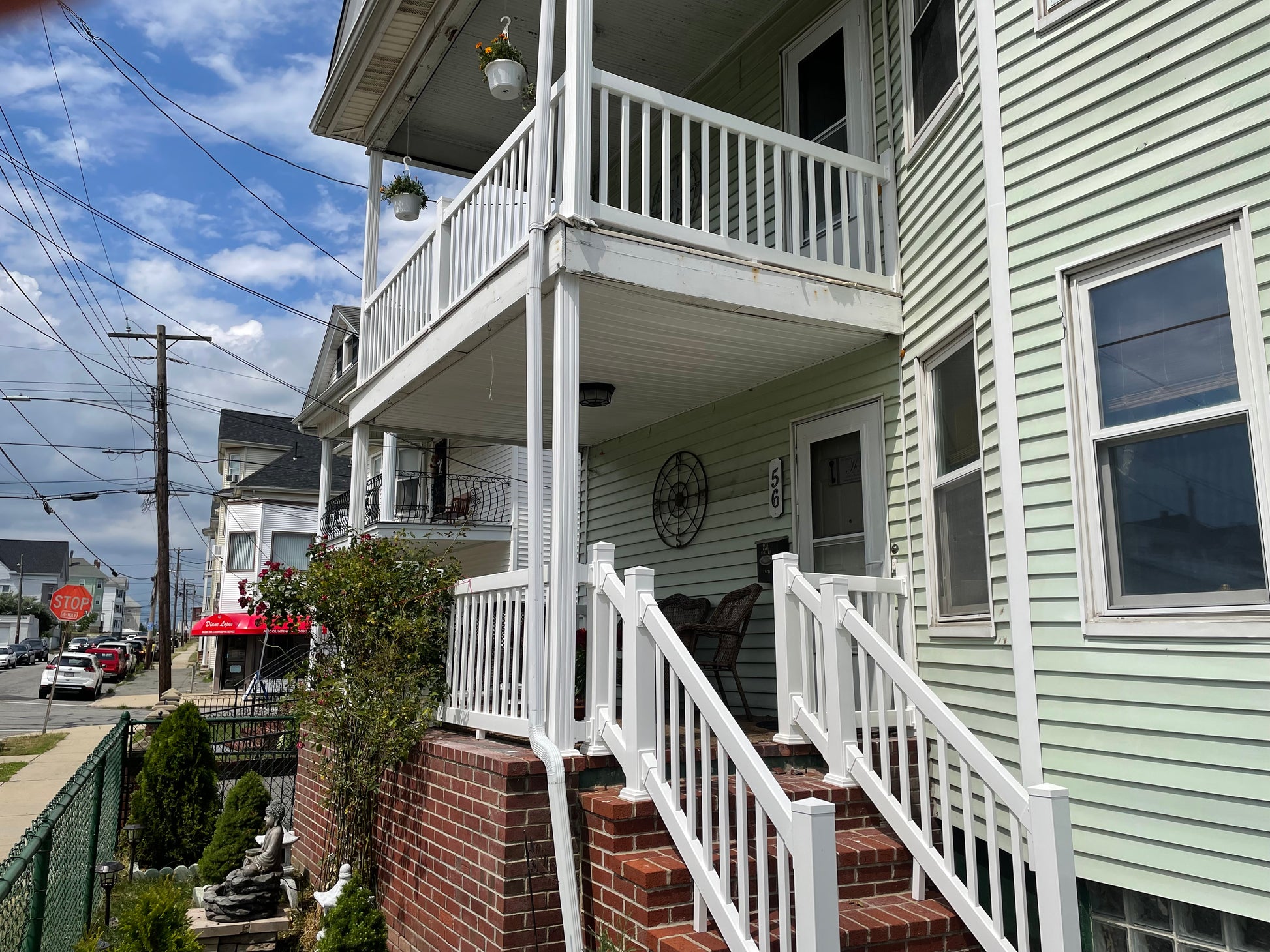 Two-story house with a white porch, Weatherables Greenwich white vinyl deck railing and staircase, surrounded by a street scene.