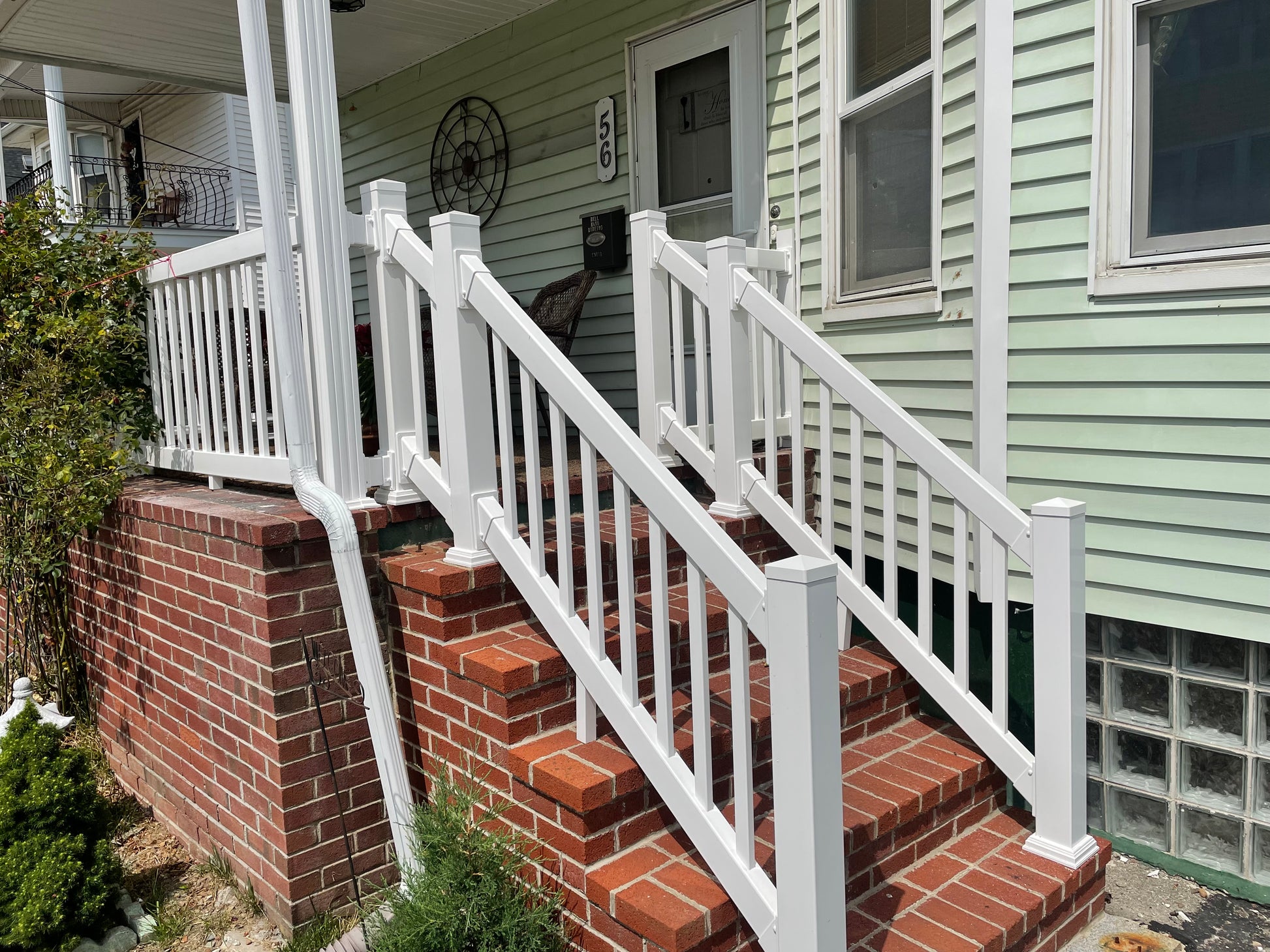Brick staircase with Weatherables Greenwich white vinyl deck railing leading to a house entrance
