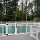 Weatherables Neptune white vinyl pool fence surrounding a pool area with trees in the background
