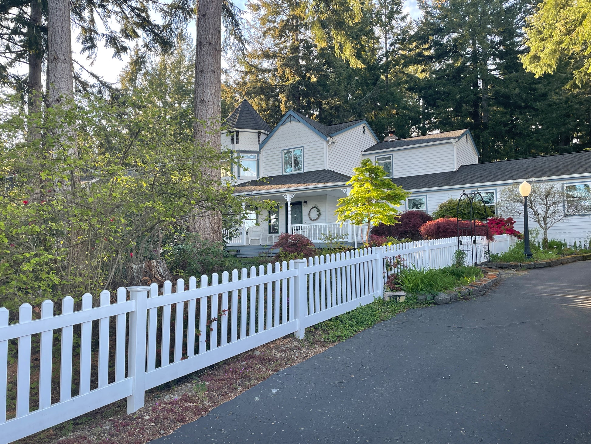 White house with a Weatherables Plymouth white vinyl picket fence and trees in the background