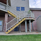 Two-story house with a staircase leading to a deck lined with Weatherables Yorkshire tan vinyl deck and stair railing