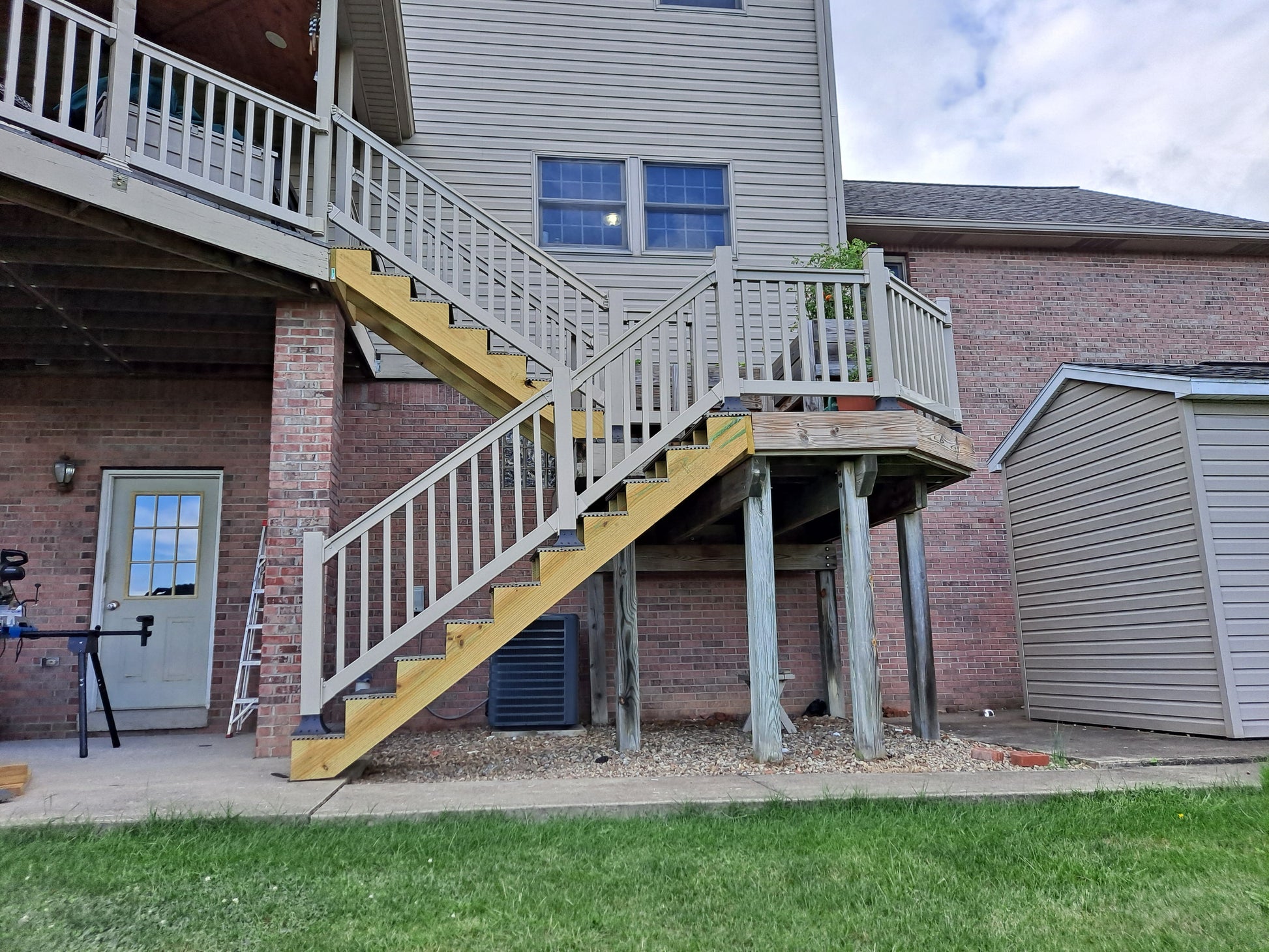 Two-story house with a staircase leading to a deck lined with Weatherables Yorkshire tan vinyl deck and stair railing