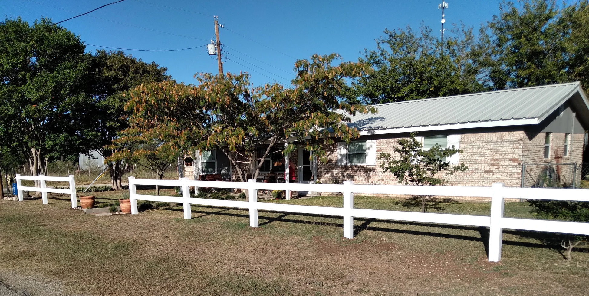 House with a Weatherables 2-rail white vinyl ranch fence and trees in the background
