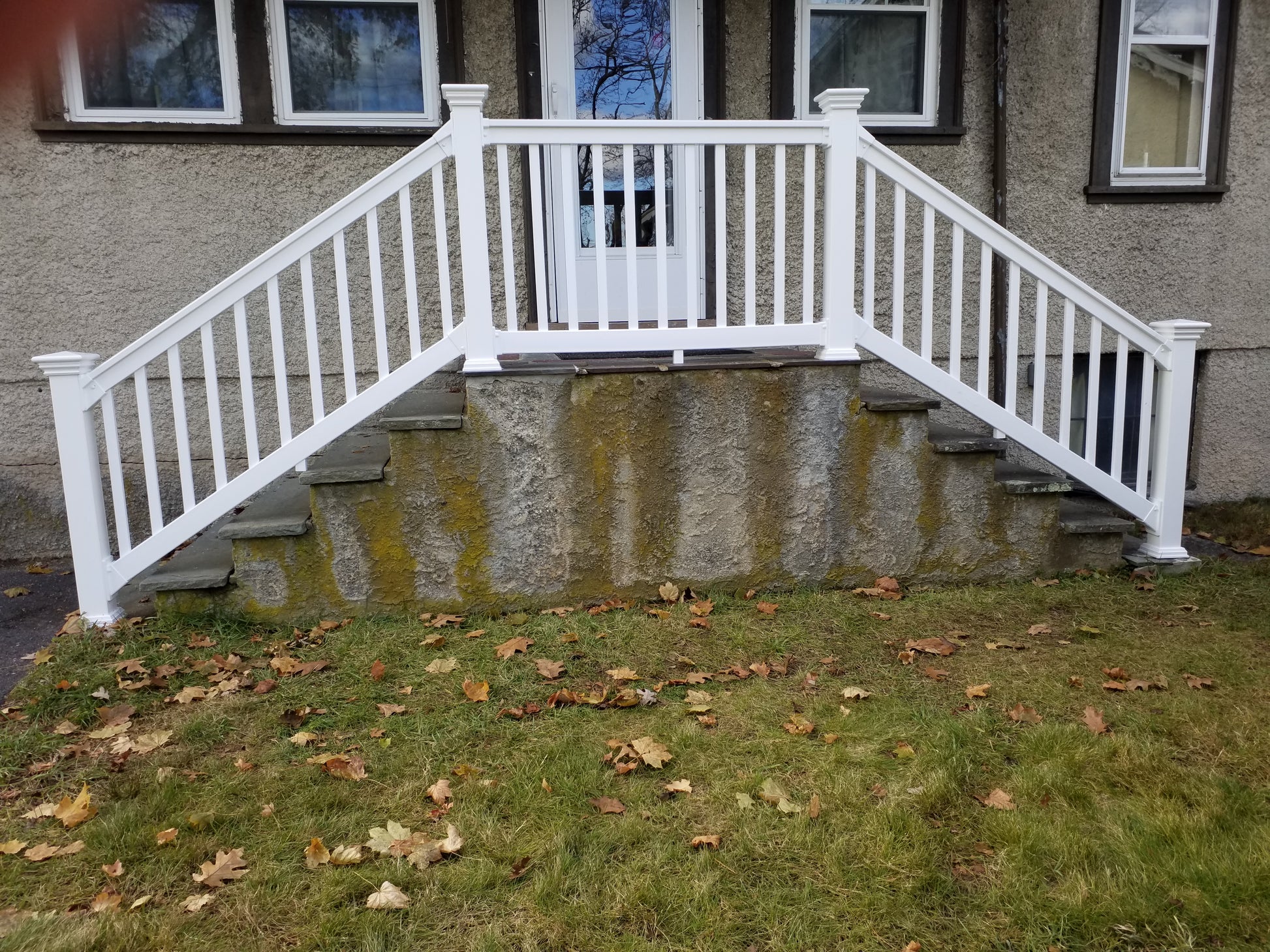Weatherables Yorkshire white vinyl porch and stair railing on a set off concrete steps leading to a front door.