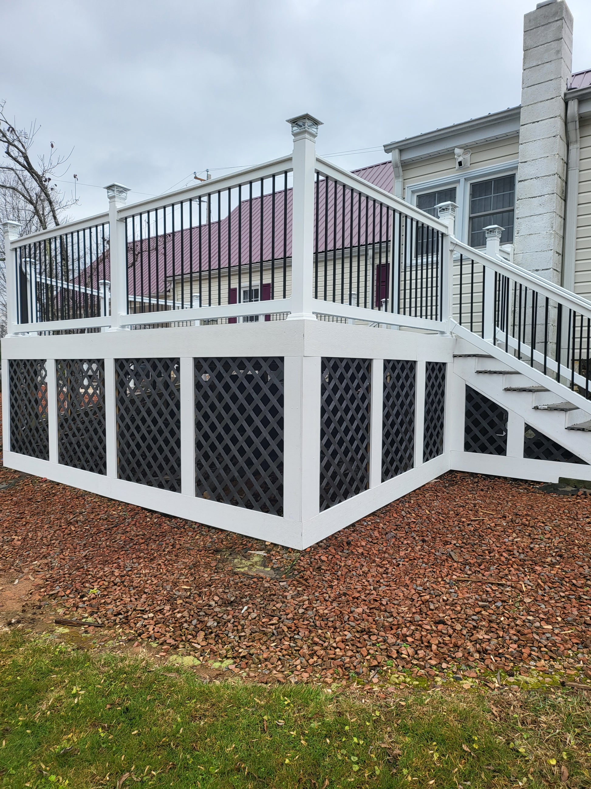 Weathrables Bolton white vinyl deck railing with black aluminum balusters in front of a house