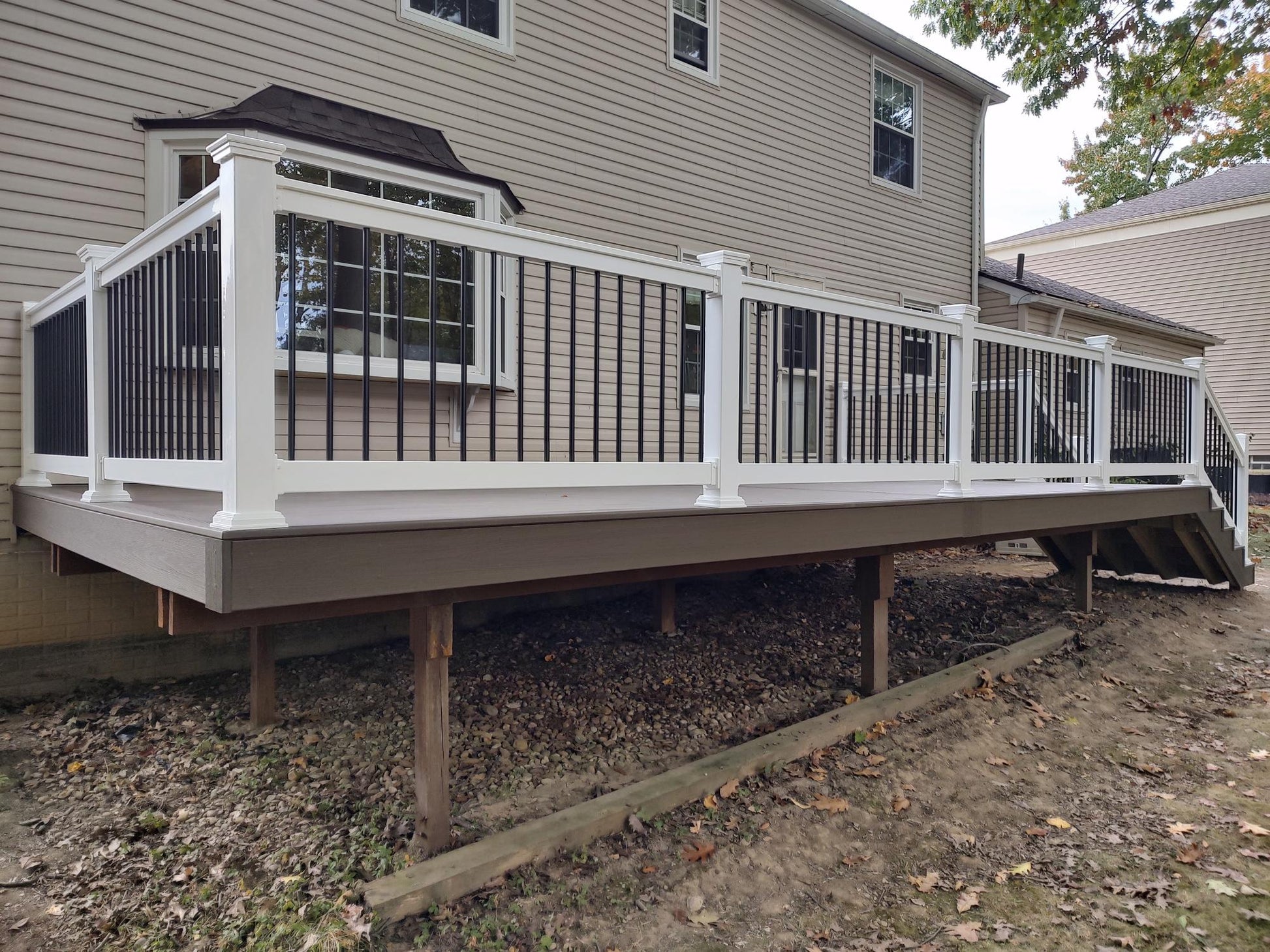 Wooden deck with Weatherables Bolton white vinyl deck railing and gazebo attached to a house.