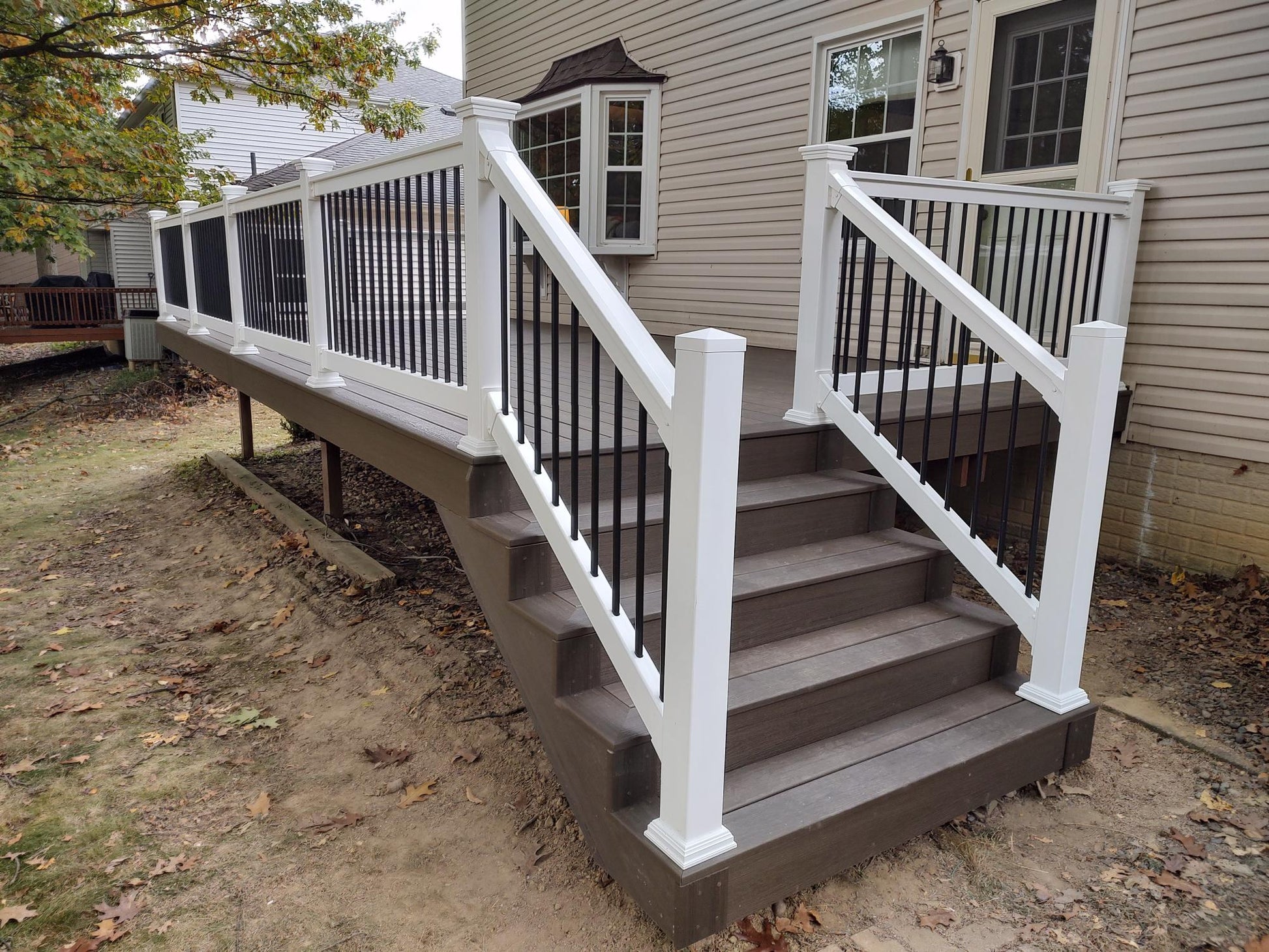 Staircase with Weatherables Bolton white vinyl deck railings leading to a deck on a house.