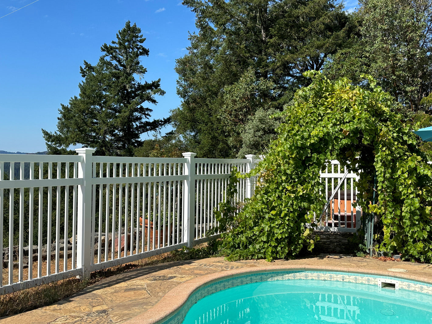Pool area with Weatherables Neptune white vinyl pool fence and greenery
