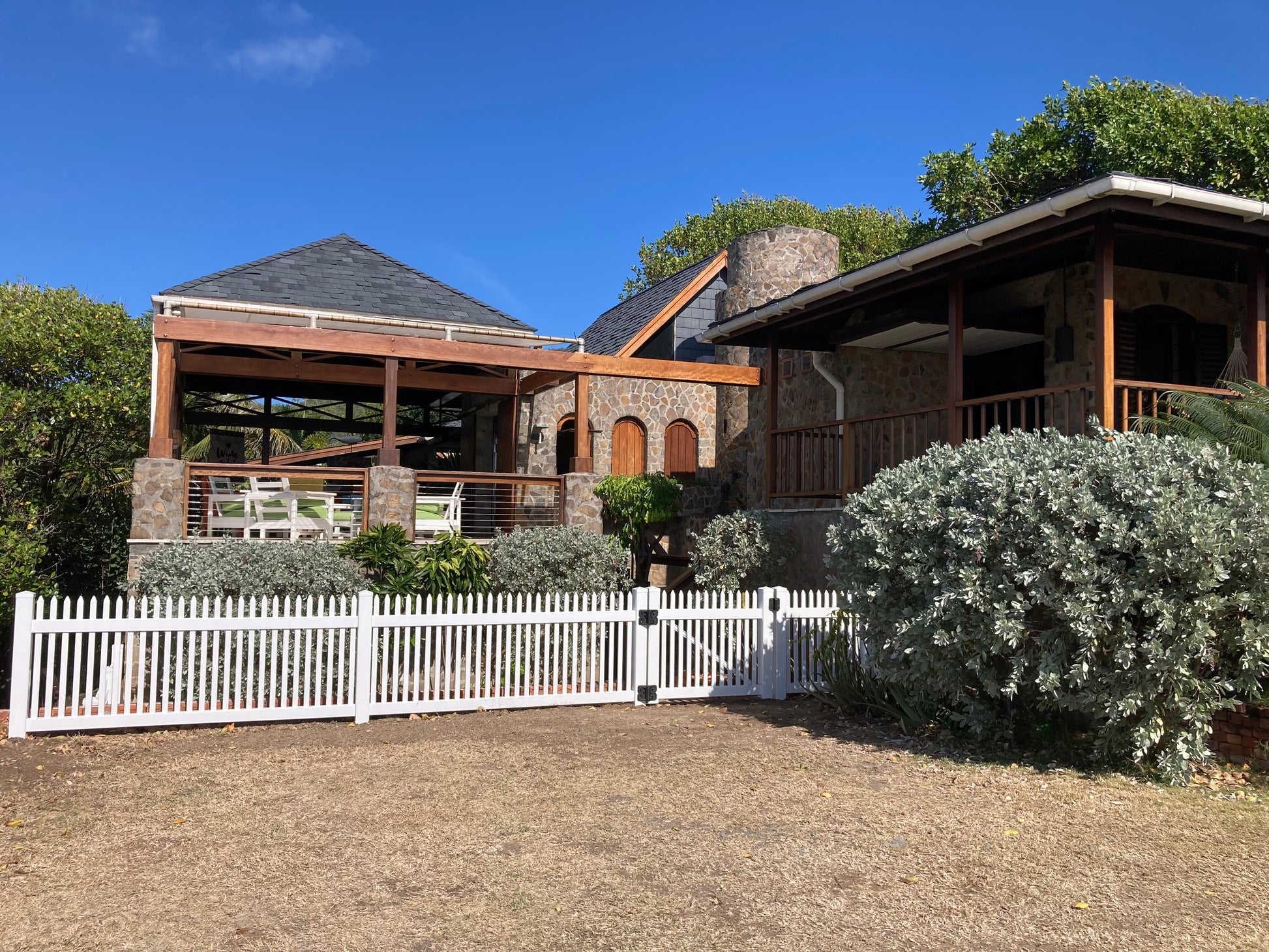 Two-story house with wooden deck and Weatherables Hartford white vinyl picket fence in a suburban setting