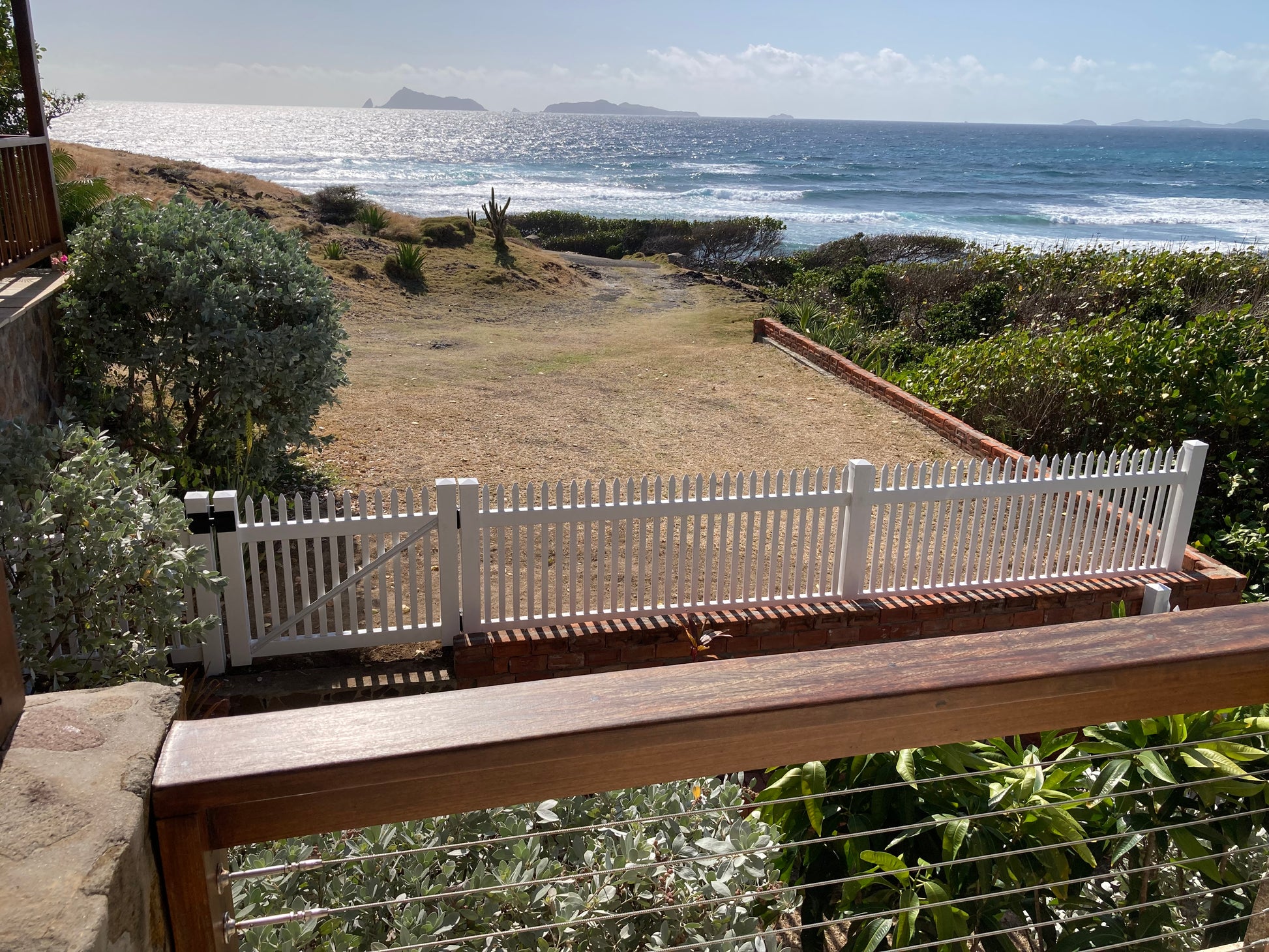 View from a balcony overlooking a coastal landscape with a Weatherables Hartford white vinyl picket fence.