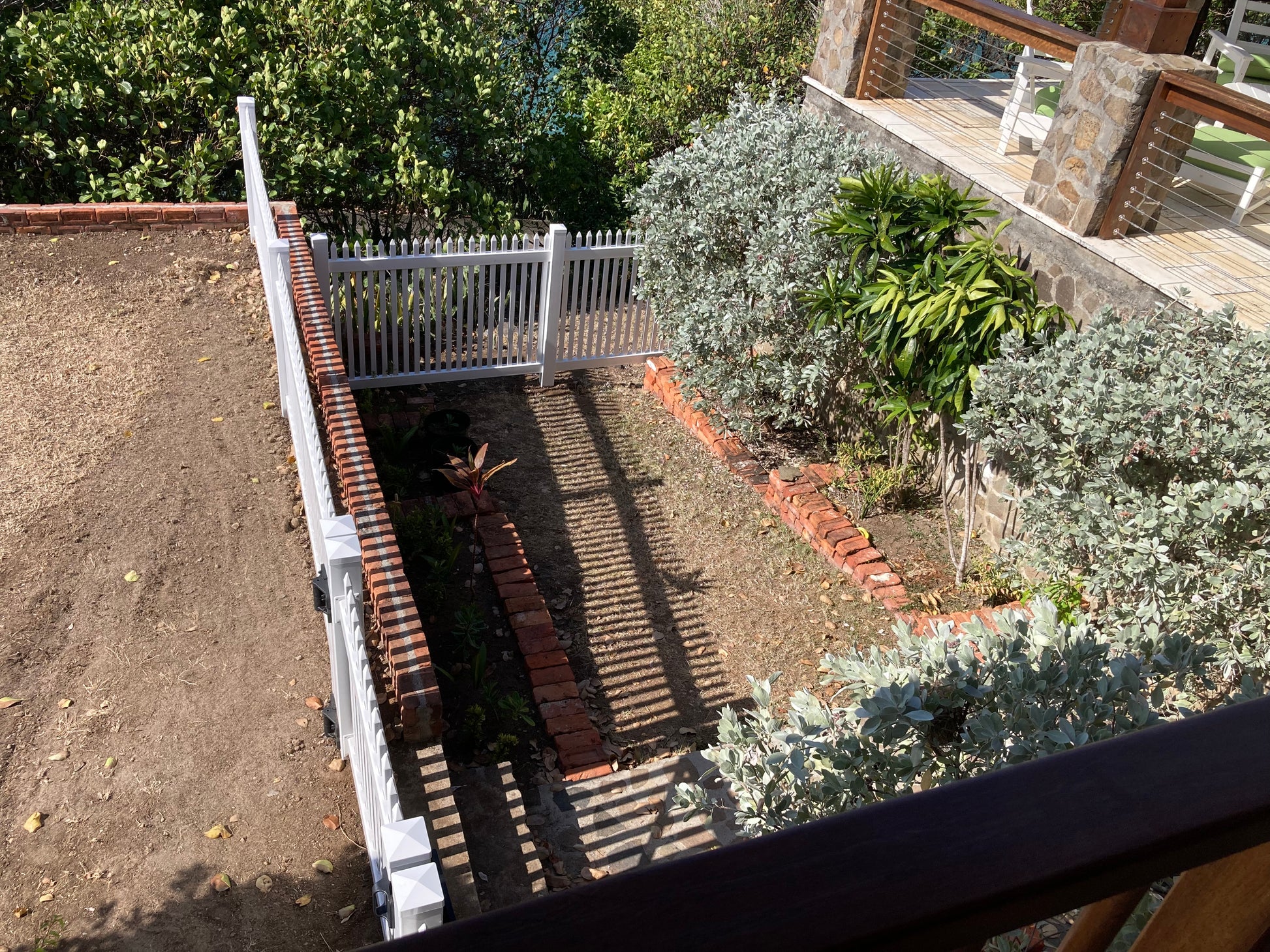 Garden with plants and a Weatherables Hartford white vinyl picket fence, viewed from above