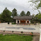 Outdoor playground with a pool, slide, and scaffolding surrounded by Weatherables Crestview tan vinyl pool fence and trees on a cloudy day.