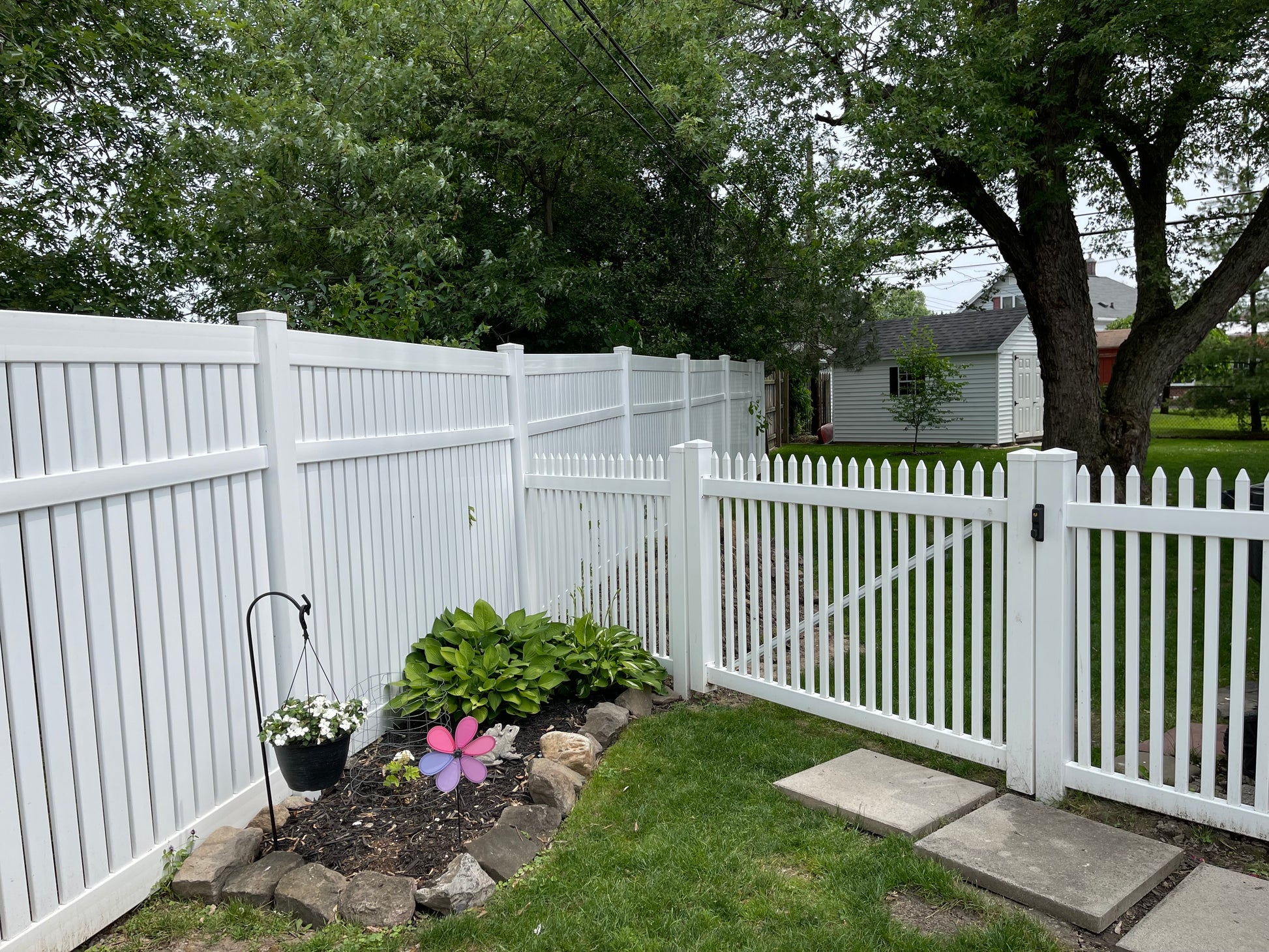 Weatherables Hartford white vinyl picket fence with garden and pathway in a residential backyard