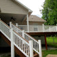 Two-story house with a large deck and Weatherables Bristol white vinyl deck railings, surrounded by trees and greenery.