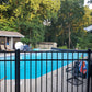 Pool area with a Weatherables Pacific black aluminum fence, chairs, and trees in the background