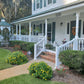 White colonial-style house with Weatherables Burlington white vinyl porch railing and garden