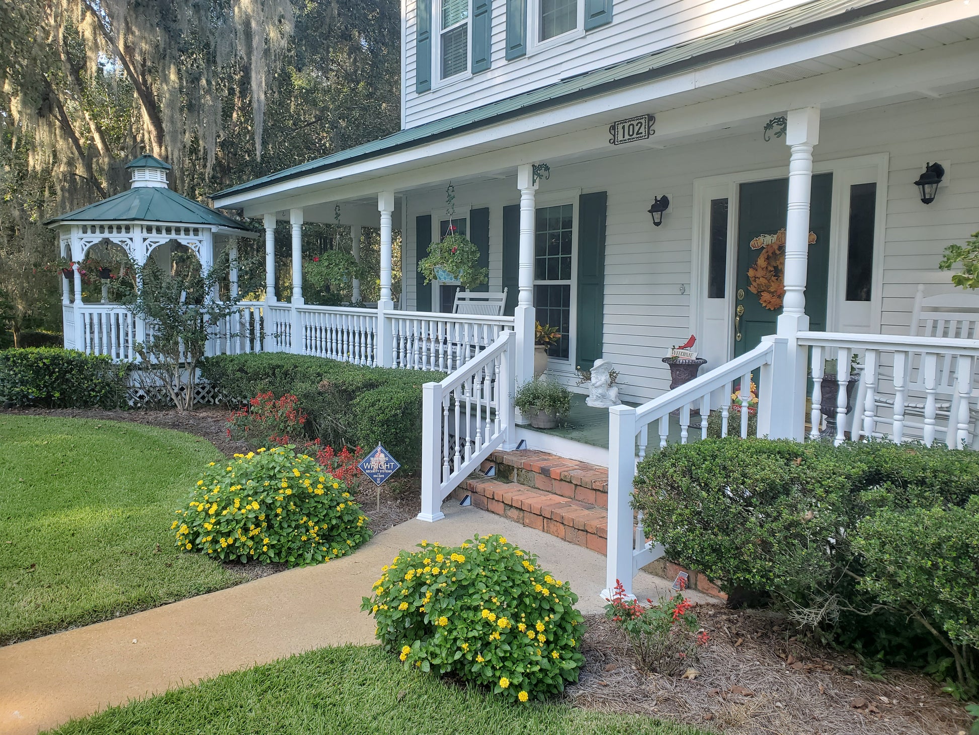 White colonial-style house with Weatherables Burlington white vinyl porch railing and garden
