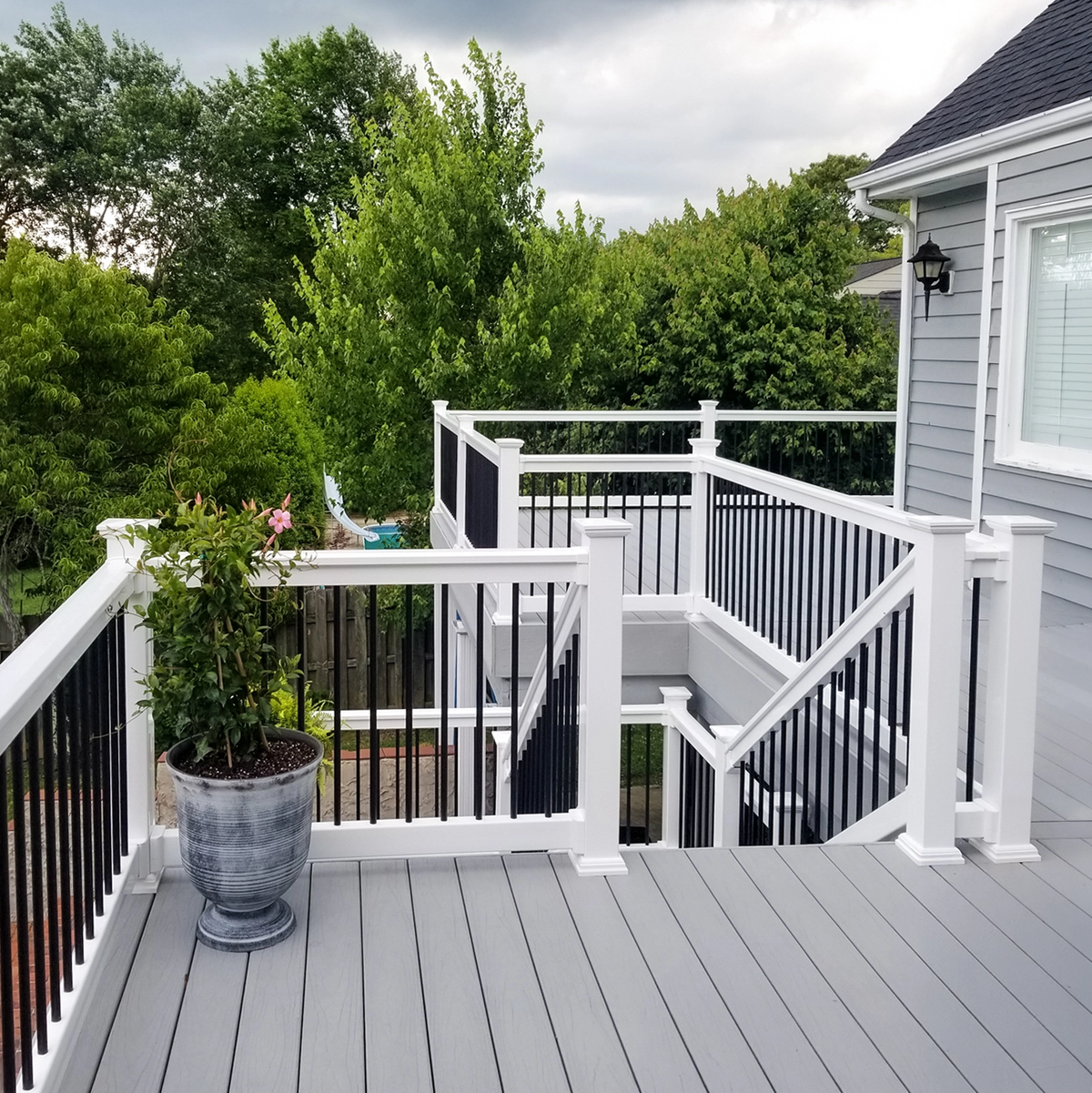 White vinyl railing with black balusters on a grey two-level deck.
