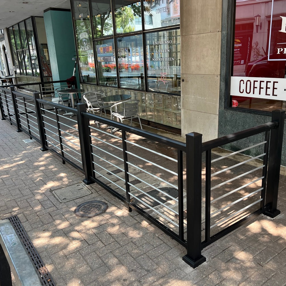 Outdoor seating area with Weatherables Cornell black and silver aluminum rod railing in front of a coffee shop.