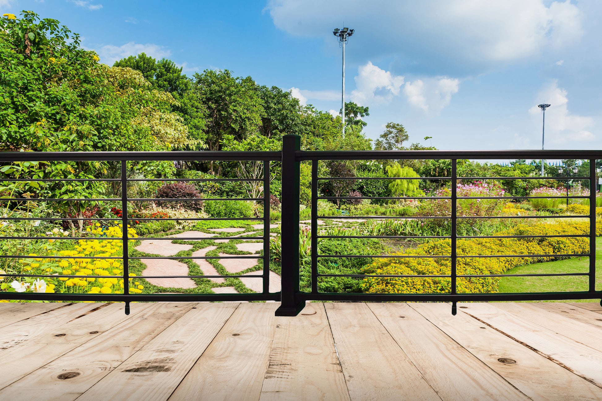 Garden view from a wooden deck with Weatherables Georgetown aluminum rod railing, featuring greenery and a clear skies