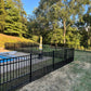 Pool area with Weatherables Terrier puppy picket aluminum fence and trees in the background