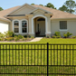 House with a Weatherables Terrier puppy picket aluminum fence in the foreground
