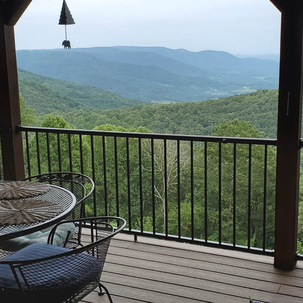 Balcony with outdoor furniture overlooking a scenic view of mountains and trees.