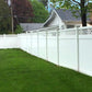 White vinyl fence along a grassy yard with a house in the background