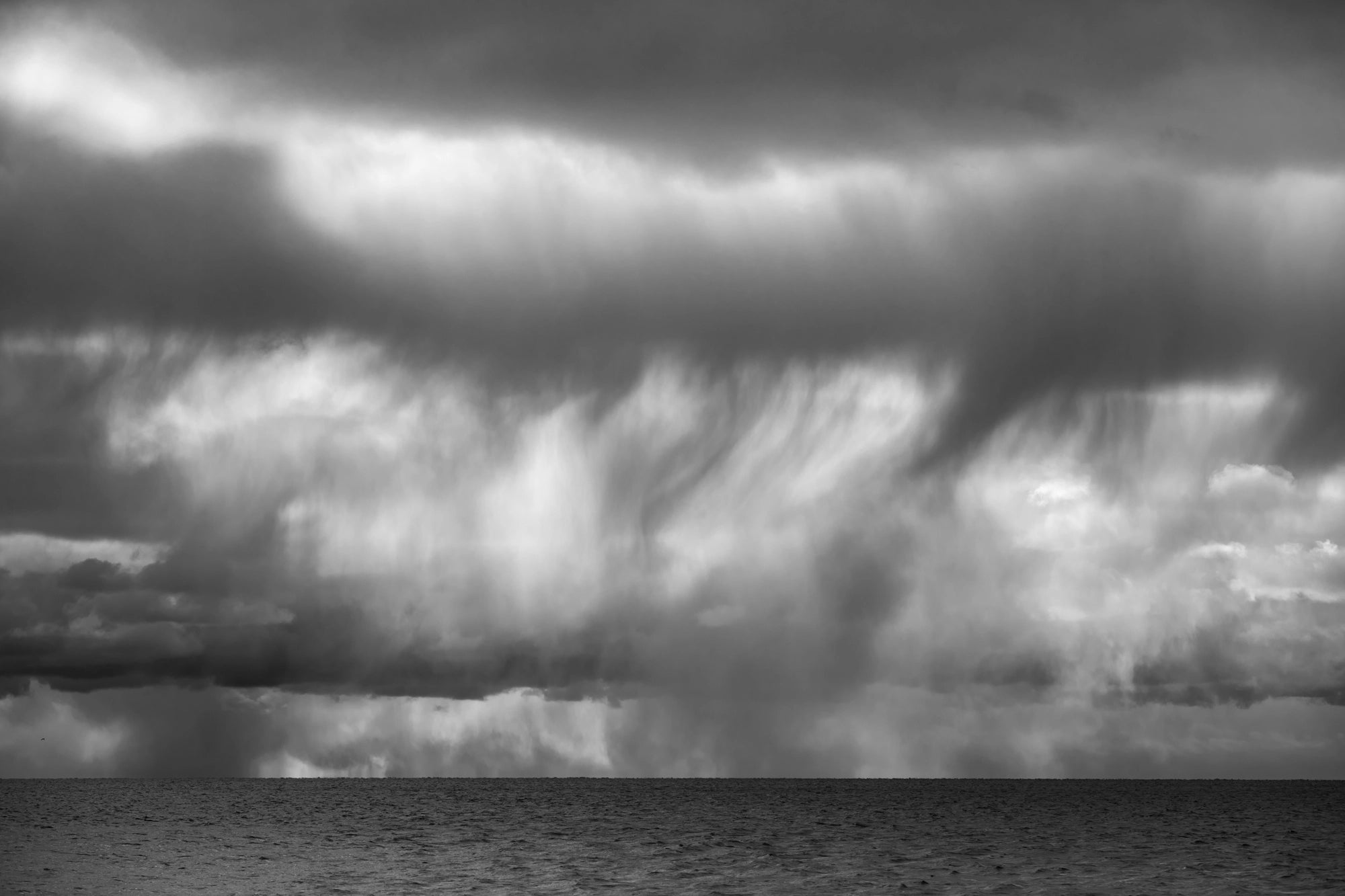 Black and white image of a large storm cloud over water