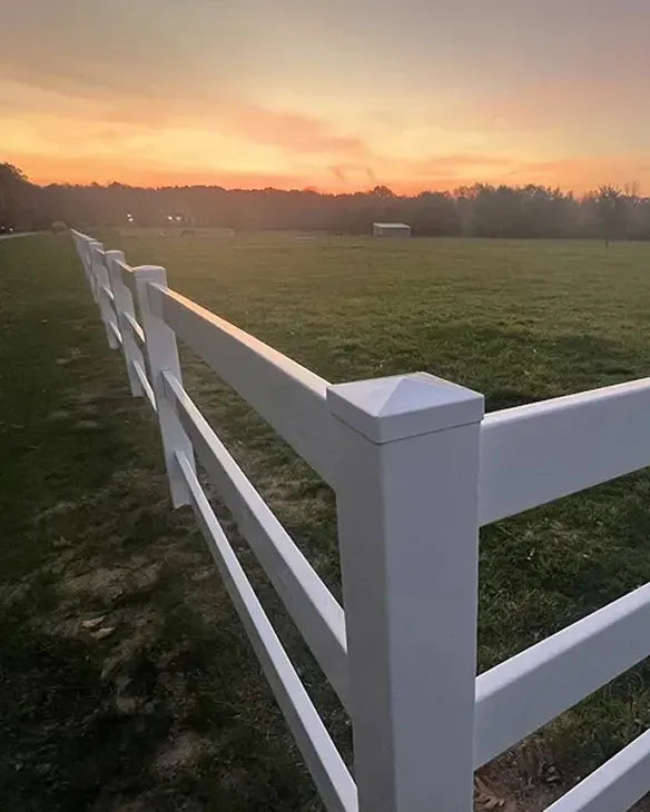 White fence in a field with a sunset sky
