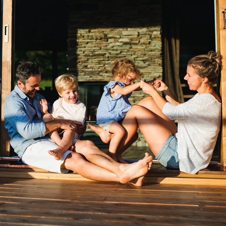 Family sitting on a wooden deck with stone wall background