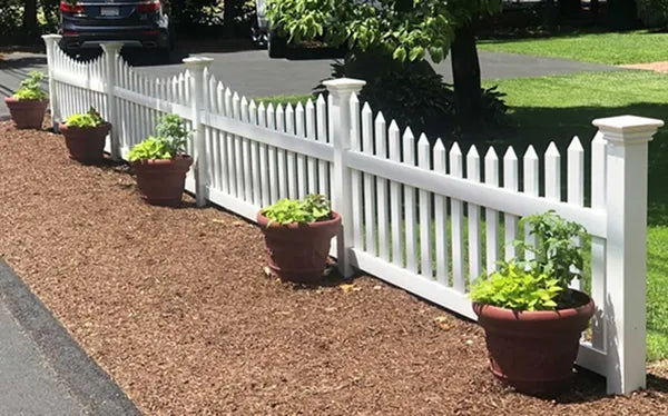 White picket fence with potted plants along a driveway