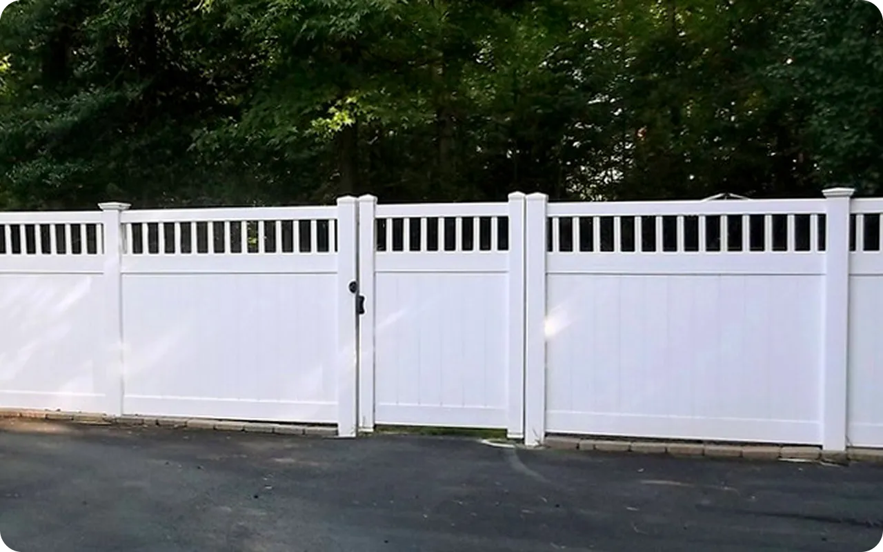 White vinyl fence with a gate in front of trees